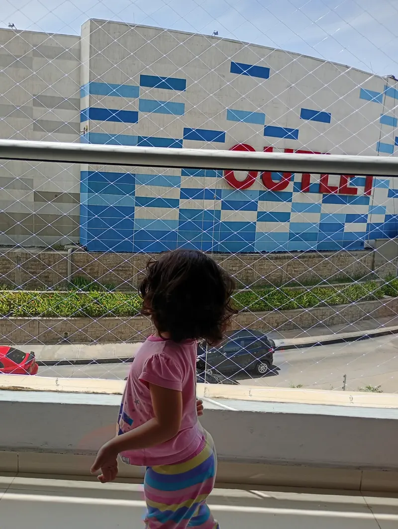 Niña jugando tranquila en un balcón protegido con malla de seguridad